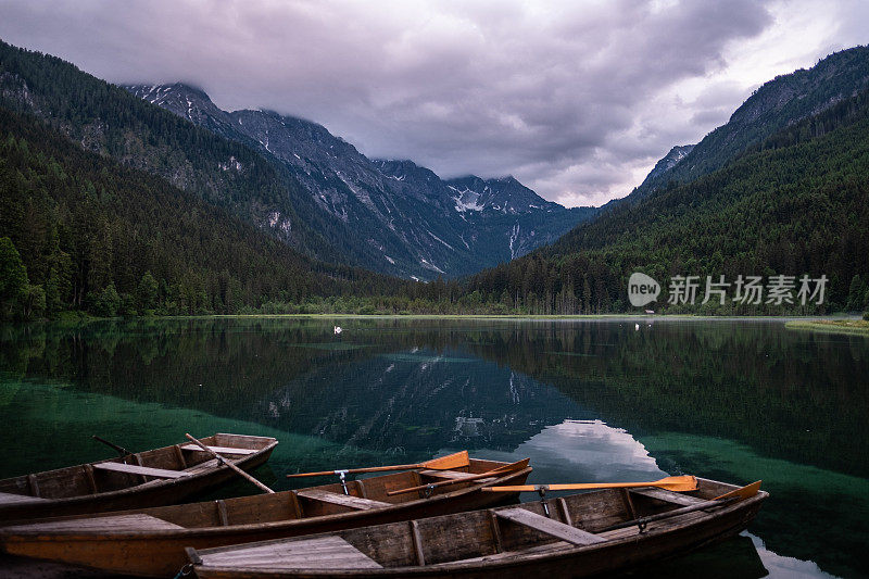 As the sun sets over the serene Jägersee in Austria, a rowing boat gently floats in the foreground, adding a sense of tranquility and calmness to the already beautiful landscape.